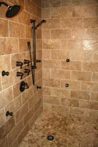 Walk-in shower with multiple shower heads and tan tile